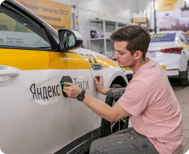 Мастер KIPARK оклеивает автомобиль для работы в такси